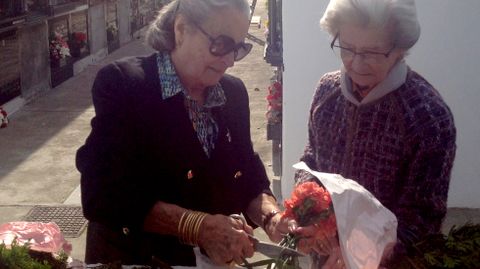 Dos mujeres arreglan unas flores en el cementerio de Gijn el da de Todos los Santos