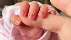 Un bebé de pocos días de edad coge el dedo de su madre