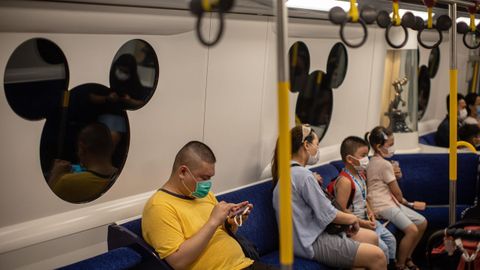 Pasajeros se sientan en un tren con destino a Disneyland en Hong Kong, China