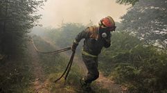 Un bombero forestal trata de protegerse del humo del incendio de Froxn, uno de los que este viernes seguan activos en el municipio de Folgoso do Courel