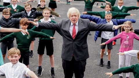 Boris Johnson visit ayer una escuela donde pos con varios alumnos con los brazos abiertos, una forma de calcular la distancia social
