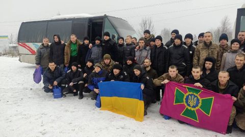 Soldados liberados de Ucrania posan con la bandera del país y otra de las Fuerzas Armadas.