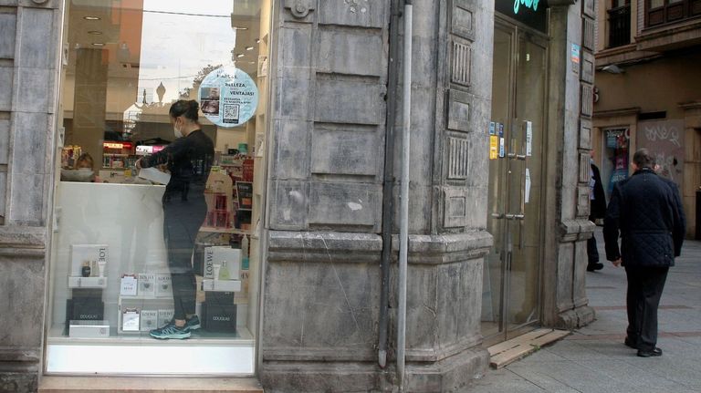 La empleada de un comercio minorista de Gijón prepara el local para abrir mañana al público