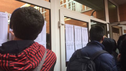 Estudiantes ojeando el listado de aulas en el examen MIR en Oviedo
