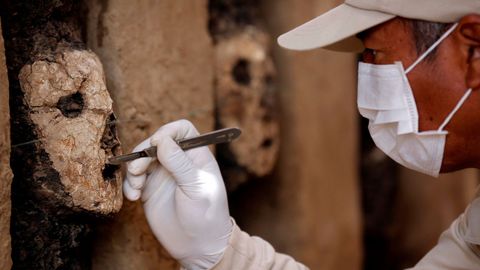 Un arquelogo limpia una mascara de madera de la cultura Mochica en el complejo arqueolgico Chan Chan en Trujillo, Per. 