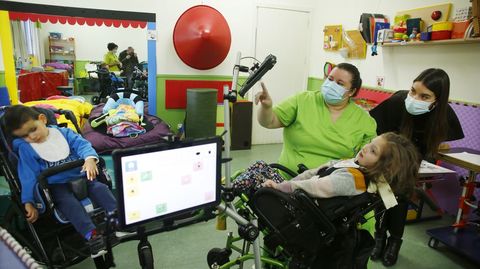 La niña Mar utilizando un comunicador audivisual, acompañada de otro niño del cole, de una profesora de Amencer y una logopeda especializada en sistemas aumentativos de comunicación.