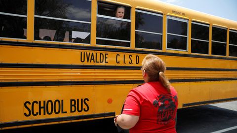 Un empleado de la escuela primaria habla a través de la ventana del bus escolar con la madre de un alumno.