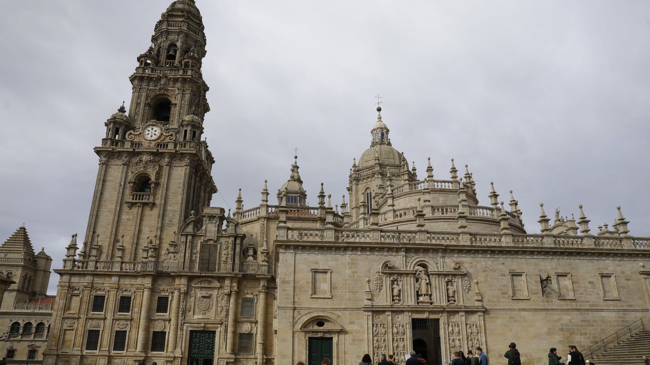 Los tableros del tres en rayaesparcidospor Compostela.Jorge Vila con un ejemplar de su libro ante la torre del homenaje y el antiguo convento de San Vicente do Pino, actual parador