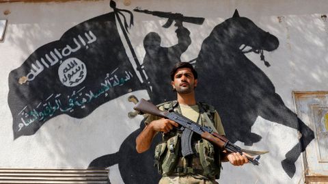Un soldado sirio monta guardia delante de un mural del Estado Islámico en la ciudad fronteriza de Yarábulus