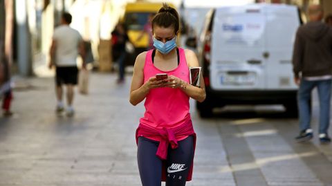 Una mujer después de practicar deporte consulta su móvil en el centro de Vigo