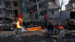 Un hombre sentado junto al fuego ante un edificio daado por el sesmo en la ciudad turca de Kahramanmaras