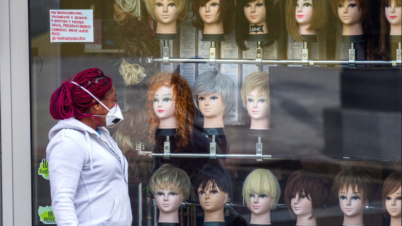  Una mujer con un carro de la compra observa un escaparate en Oviedo