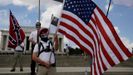 Un manifestante sostiene una bandera de EE.UU. delante de otros que agitan una bandera confederada y otras banderas vinculadas a la supremacía blanca