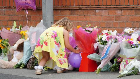 Una niña deja flores como tributo a la pequeña Olivia, asesinada de un tiro en su casa de Liverpool