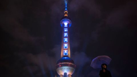 Una mujer con un paraguas en las inmediaciones de la torre de la perla en Shanghai (China).