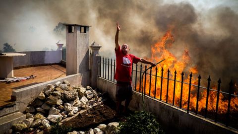 Un vecino peda ayer que arrojaran agua sobre las llamas que cercaban su casa en Canecas.
