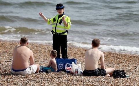 Una agente britnica invita a unos baistas a abandonar el arenal de Brighton, en el sur de Inglaterra