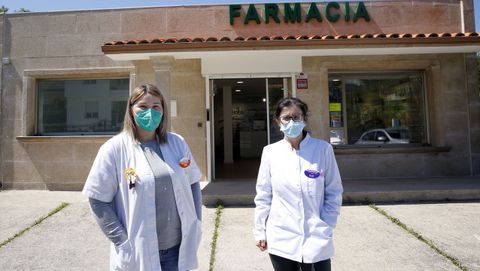 Ana Romero y Margarita Goldar posan delante de la farmacia, que ayer reabrió sus puertas