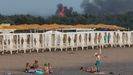 Veraneantes toman el sol en una playa de Crimea con el incendio, al fondo, de la base aérea rusa