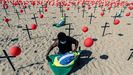 Un hombre instala una bandera de Brasil en una representacin escnica de la ONG Ro de Paz por las 100.000 vctimas mortales del covid en el pas