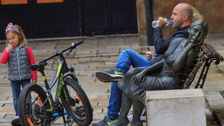 Una hombre descansa en un banco después de un paseo en bici con su hija en la plaza Trascorrales de Oviedo