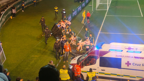 Momento en el que jugadores de los dos equipos ayudan a retirar las vallas publicitarias para que entre la ambulancia