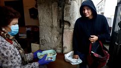 Un usuario del comedor social de Pontevedra recogiendo un tper de comida a la puerta del convento.