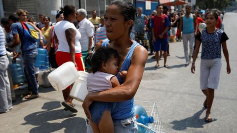 Una mujer cargando con su beb se dispone a hacer cola para aprovisionarse de agua en Caracas