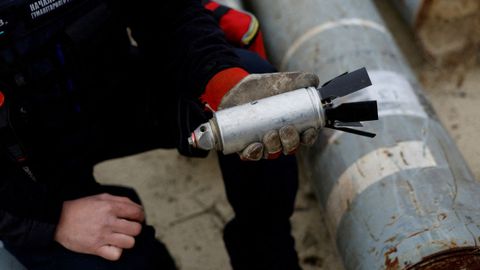 A Ukrainian soldier holds a deactivated cluster bomb dropped by the Russian army in the Kharkiv region