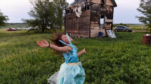 Una nia juega junto a una casa abandonada en Green Grass (Dakota del Sur)