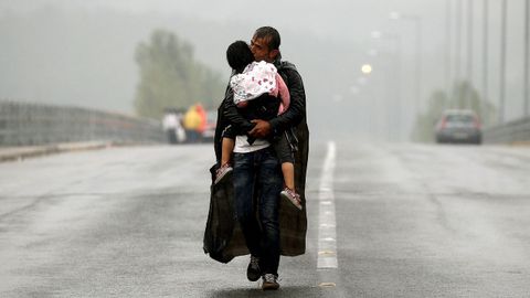 Un refugiado sirio besa a su hija mientras camina bajo la tormenta hacia la frontera de Grecia con Macedonia.