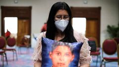 Una mujer de El Salvador sostiene una almohada con la fotografa de su hijo desaparecido en El Salvador.