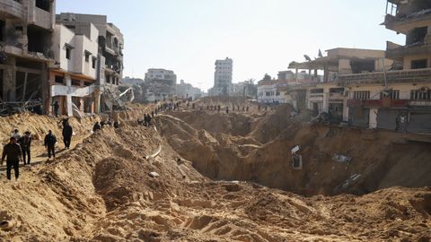 Palestinos atraviesan una calle bombardeada en Gaza.