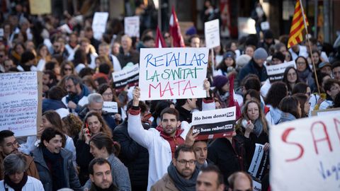 Varias personas protestan con pancartas y batas blancas durante una manifestación del sindicato Médicos de Cataluña por la huelga sanitaria