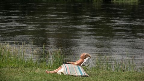 Una mujer disfruta de las agradables temperaturas en la zona fluvial del río Miño y las termas de A Chavasqueira