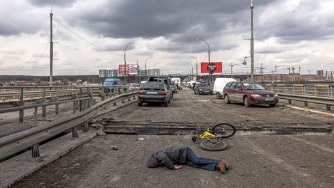 El cuerpo de un yace en la carretera cerca en un puente con coches abandonados en un puente de la ciudad de Irpín, cerca de Kiev