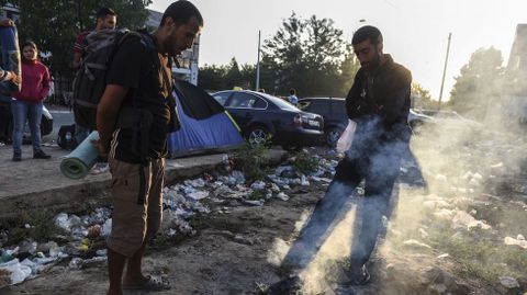 Inmigrantes sirios esperan al lado de un fuego extinto en Presevo, despus de caminar desde Macedonia hasta Serbia