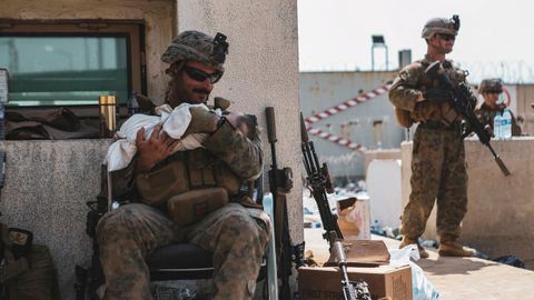 El sargento Isaiah Campbell sostiene al bebé tras recogerlo del muro del aeropuerto de Kabul.