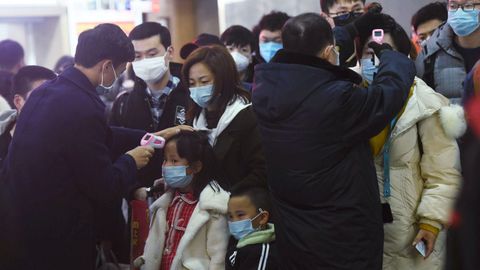 Los miembros del personal verifican la temperatura corporal de los pasajeros que llegan del tren de Wuhan a Hangzhou, en la estación de tren de Hangzhou