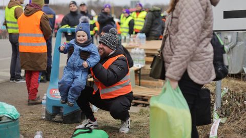 Un voluntario juega con un nio en la frontera de Ucrania con Eslovaquia 
