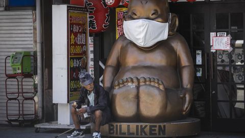 Un hombre, ayer, sentado junto a la deidad local Billiken, de Osaka