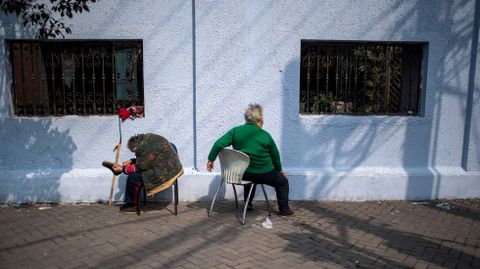 Dos mujeres mayores disfrutan del sol frente a un muro en Shanghai