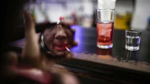 Imagen de una prostituta que se maquilla en la barra de un bar