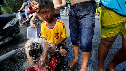 Un grupo de nios usa una tubera de agua para baarse en un campamento para personas desplazadas por un terremoto y un tsunami en Palu, Indonesia