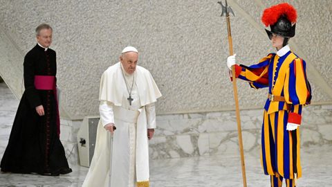 El papa Francisco pasa andando delante de un guardia suizo en el Vaticano