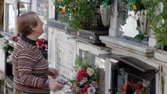 Una mujer arregla ofrendas florales en la tumba de un familiar en el cementerio de Ceares de Gijn