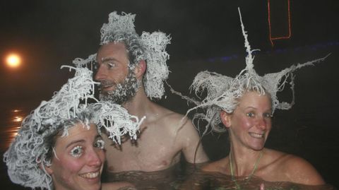 Tres personas con escarcha en el pelo y las cejas bandose en una piscina de agua caliente con temperaturas de menos treinta grados en Canad. 