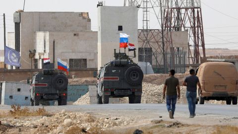 Vehículos militares con banderas rusas y sirias pasan por el antiguo cuartel de la tropas estadounidenses en Manbij