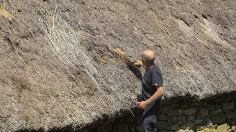 Un propietario, Ernesto, muestra lo deteriorado que est el techo de su palloza. 