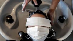 Una mujer acude a la peluquera ataviada con mascarilla